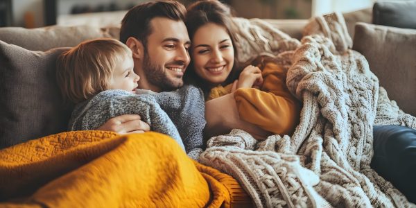 A close knit family snuggled up on a cozy couch wrapped in a soft blanket as they watch the Thanksgiving Day Parade on television embodying the warmth and tradition of the holiday season
