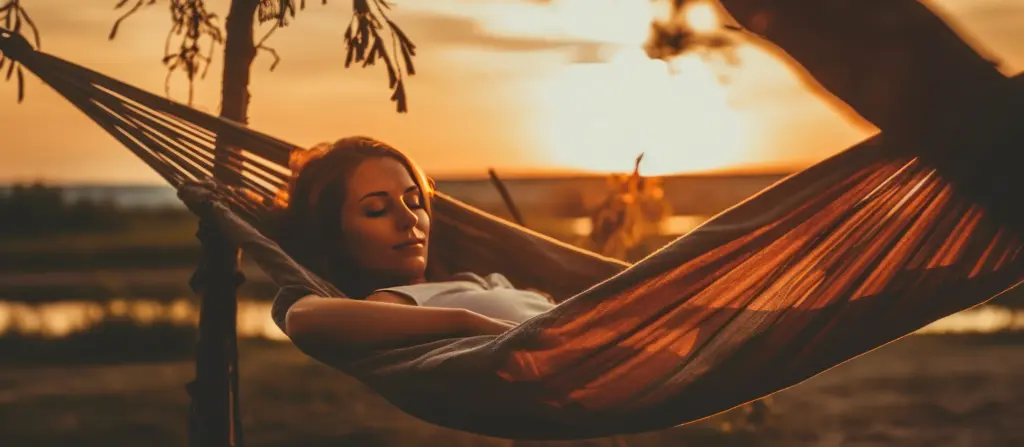 Eine Frau entspannt mit geschlossenen Augen in einer Hängematte bei goldenem Sonnenuntergang – Ruhe und tiefe Entspannung finden mit Zukunfts-Impuls.